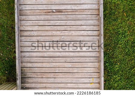 wooden boardwalk over lawn with green grass, modern park background, top view