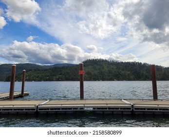 Wooden boat dock at lake boat launch with pylons and cloudy sky. 