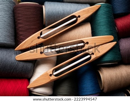 Wooden boat shuttles and bobbins with multicolored yarn, selected focus. Weaving shuttles waiting for work