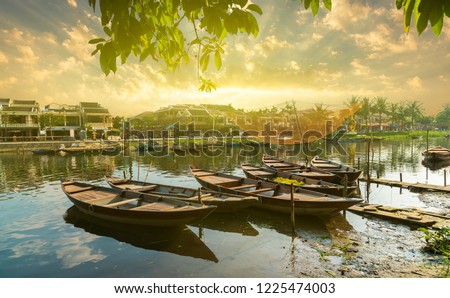 Wooden boats on the Thu Bon River in Hoi An Ancient Town,  Vietnam. Yellow old houses on waterfront reflected in river. Vietnam 
