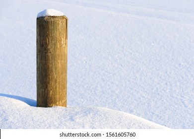 Wooden Bollard And Pier Covered With Snow.