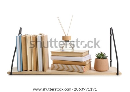Wooden book shelf with flowerpot and reed diffuser on white background
