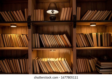 Wooden Bookcase With Books. On The Shelves There Are Many Different Books Illuminated By Warm Light. Home Library.