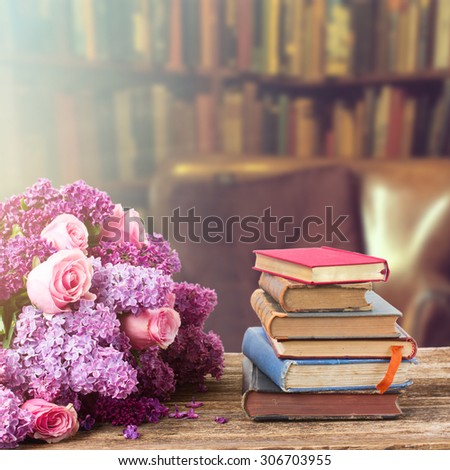 Wooden bookshelf  with stack of antique books and flowers in library