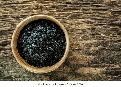 A wooden bowl filled with Hawaiian Lava Salt crystals, a sea salt coloured black by the volcanic lava and blended with deactivated charcoal , used as a decorative spice and condiment in cooking