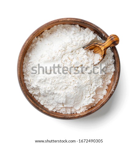Wooden bowl with flour and flour spoon. Rice or wheat flour isolated on white background. top view