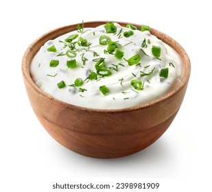 Wooden bowl of fresh sour cream dip sauce with herbs and green onions isolated on white background