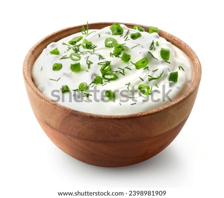 Wooden bowl of fresh sour cream dip sauce with herbs and green onions isolated on white background