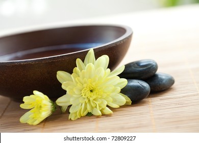 Wooden bowl with hot stones and chrysanthemum for spa - Powered by Shutterstock