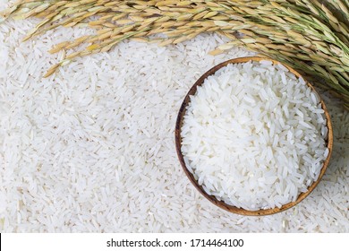 Wooden bowl with rice on rice and rice ears background with copy space for your text, top view. Natural food high in protein