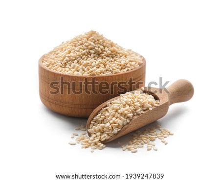 Wooden bowl and scoop with sesame seeds on white background