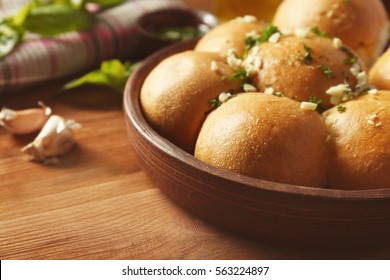 Wooden bowl with tasty garlic bread rolls on kitchen table - Powered by Shutterstock