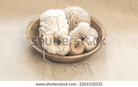 Wooden bowl with threads for knitting yarns close-up.
