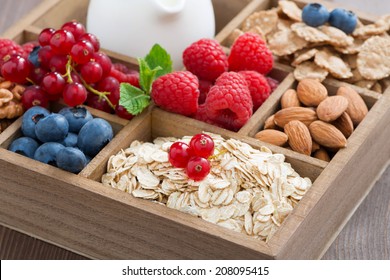 wooden box with breakfast items - oatmeal, granola, nuts, berries and milk, close-up, horizontal