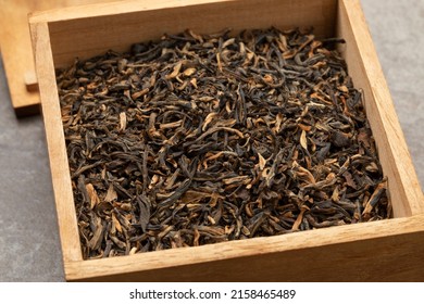 Wooden box with dried Chinese Yunnan Mao Feng tea close up 