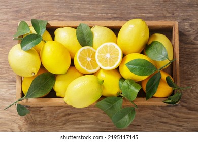 wooden box of fresh lemons with leaves on a wooden background, top view - Powered by Shutterstock