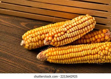 Wooden Box Full Of Potatoes And Corn Cobs On Dark Wooden Background