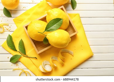 Wooden Box With Juicy Citrus Fruit, Green Leaves And Lemon Zest On Table