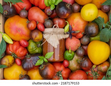 Wooden Box With Mix Of Multicolored Ripe Tomatoes Stands On The Garden Bed. Fresh Tomato, Basil With A Jar Of Ketchup For Sale At The Farmers Market. Concept Of Gardening And Delivery Of Organic Food