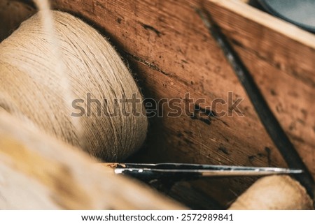 A wooden box with a spool of thread and scissors inside. The box is filled with various items, including a pair of scissors and a spool of thread. Concept of creativity and craftsmanship