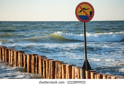 Wooden Breakwaters. Sign Forbidding Jumping From Breakwaters Into The Sea. Beach Hazard Warning Sign.