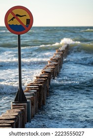 Wooden Breakwaters. Sign Forbidding Jumping From Breakwaters Into The Sea. Beach Hazard Warning Sign.