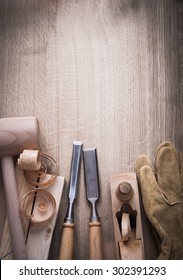 Wooden bricks hammer curled up scobs planer firmer chisels leather gloves on wood background construction concept.