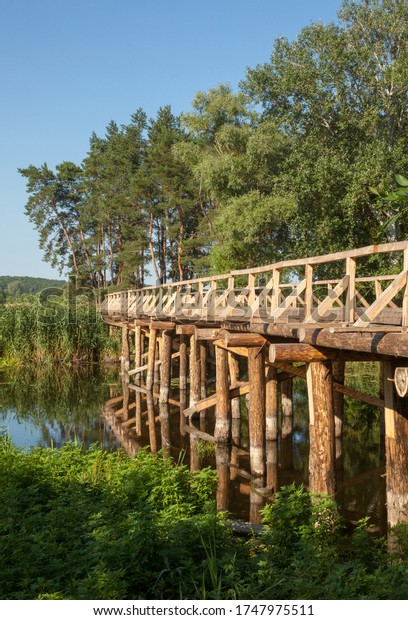 Wooden\
bridge across the river Vorskla (Ukraine) in the country. Bridge\
for cars and pedestrians. Road across the\
river.