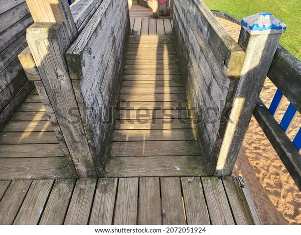 A wooden bridge area in a playground. The wooden\
walk way is from the perspective of a child playing in the fort\
like jungle gym.