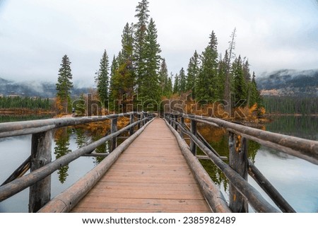 Wooden bridge crossing the island of Pyramid Lake, pine trees lined in Jesper Park, Rocky Mountains, Canada.