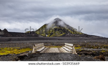 Wooden bridge in Iceland on hill background with cloudy sky
