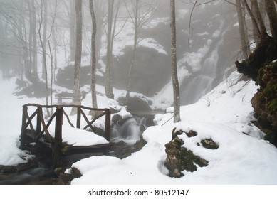 wooden bridge near the waterfall covered with snow - Powered by Shutterstock