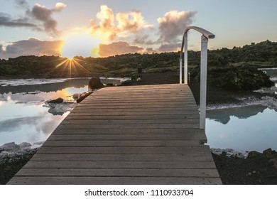 Wooden bridge with one side rail across over geothermal lagoon at sunset time golden cloud makes awesome reflection in water - Powered by Shutterstock