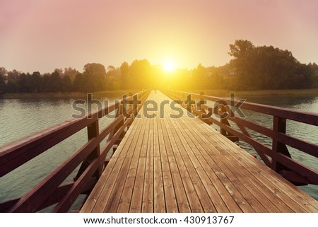 Wooden bridge over lake in early misty morning