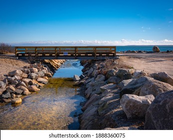 Wooden Bridge Over Rocky Brook With View Of Ocean And Blue Sky