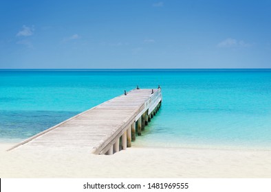 Wooden Bridge Or Pier On Tropical White Sand Beach With Clear Blue Sea And Sky On Sunny Day. Boardwalk Into The Ocean And Turquoise Water. Summer Holidays Background With Copy Space. Kuramathi Island.