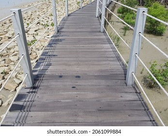 A Wooden Bridge With A Rope Handle On A Rocky Beach In The Pontian District Of Malaysia