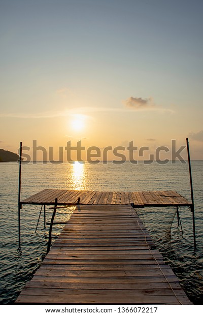 Wooden bridge in the sea and Golden reflections of\
the Sun