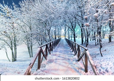 Wooden Bridge In A Snowy Park In The Evening