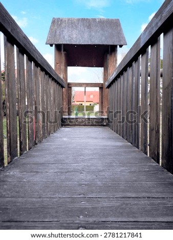 A wooden bridge and tower on a children's playground.