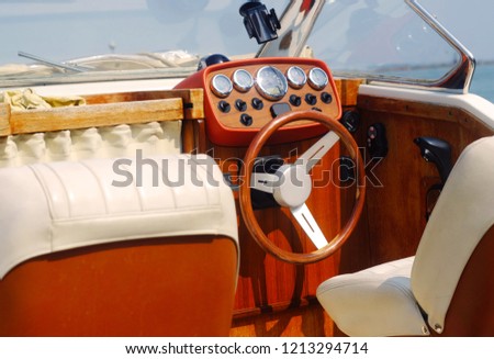 wooden brown saloon of the boat sheathed in white leather with a panel and steering wheel to control the boat, the theme of transport and vintage
