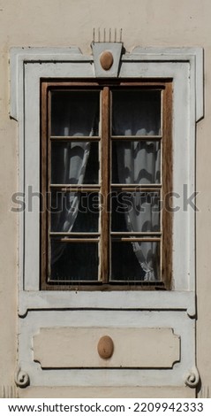 Wooden brown windown in historic building in Prague with 8 prat glass tiles and curtain inside. Texture of window in creamy facade building with ornates and spikes against birds pigeons. 