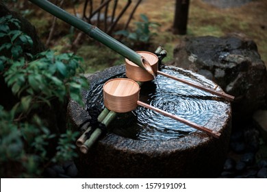 a  wooden bucket filled with water for visiters to wash hands and drink water in a japanese shinto shrine temple in Kyoto, Kansai, Japan