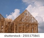 A Wooden Building Construction Frame against a Blue Cloudy Sky 