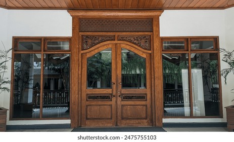 Wooden building doors with beautiful handmade carved ornaments with a combination of glass reflections from the windows - Powered by Shutterstock