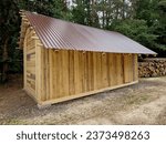 The wooden building is a hayloft built of planks and standing in a meadow with a metal roof. wood is chopped and put in the woodshed. log and pickaxe a day on the ranch