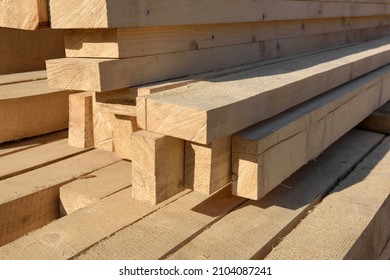 Wooden building materials close up.
A stack of natural wooden boards at a construction site. Industrial edged timber. Wooden rafters for renovation or construction. Roofing and carpentry lumber.