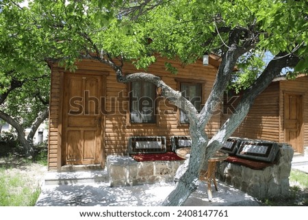 Wooden Bungalow with a Seating Area under a Tree on a Sunny Day in Cappadocia, Turkiye