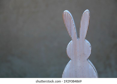 Wooden bunny and concrete wall, minimal Easter decoration. Selective focus, copy space.