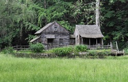Wooden Cabin In Woods With Pond And Grass In Front